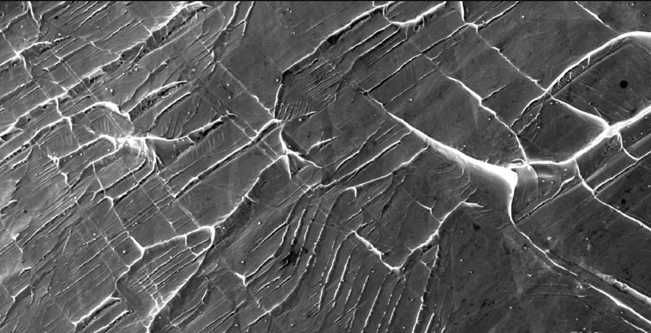 Electron microscopy image showing new defects forming between neighbouring crystals of the niobium-titanium-based alloys.