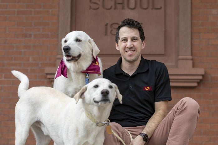 Arizona State University researcher Noah Snyder-Mackler poses with his dogs, Homer (bottom) and Juno (top). His latest study analyzed aging data from 864 dogs enrolled in the Dog Aging Project. 